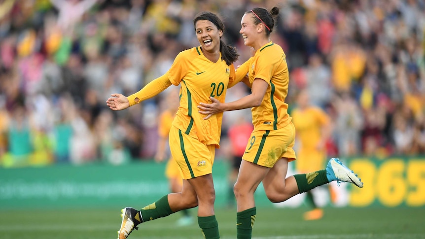 Sam Kerr smiles as she and Caitlin Foord celebrate a Matildas goal against Brazil.