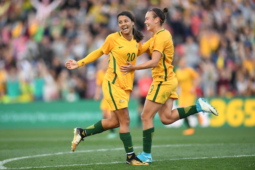 Sam Kerr smiles as she and Caitlin Foord celebrate a Matildas goal against Brazil.