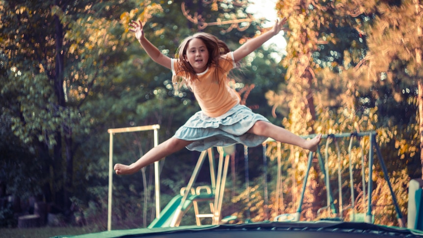 A young girl jumping on a trampoline