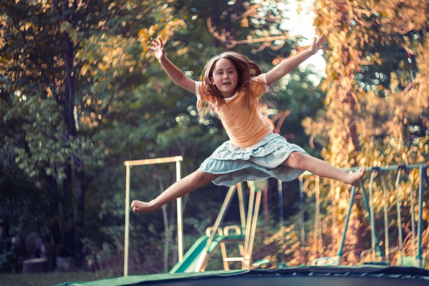 A young girl jumping on a trampoline