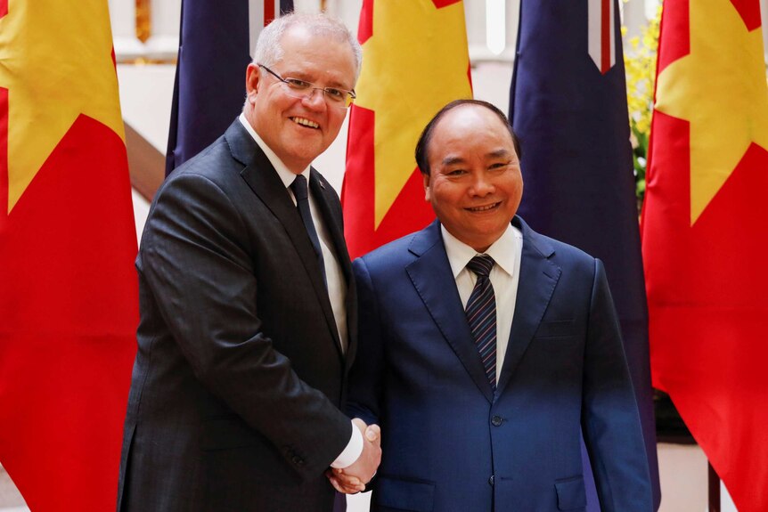 Scott Morrison shakes hands with Nguyen Xuan Phuc in front of Australian and Vietnamese flags.