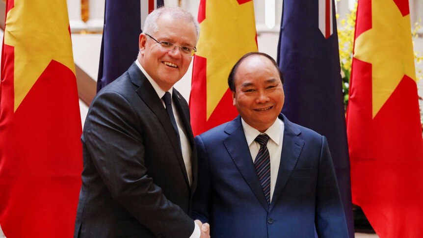 Scott Morrison shakes hands with Nguyen Xuan Phuc in front of Australian and Vietnamese flags.