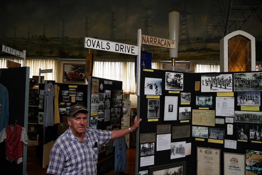 A man leaning on signpost in a room full of memorabilia.