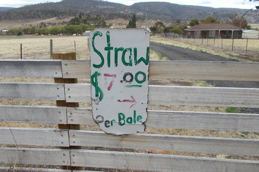 Sign advertising straw attached to wooden fence