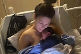 woman in hospital, cuddling a baby