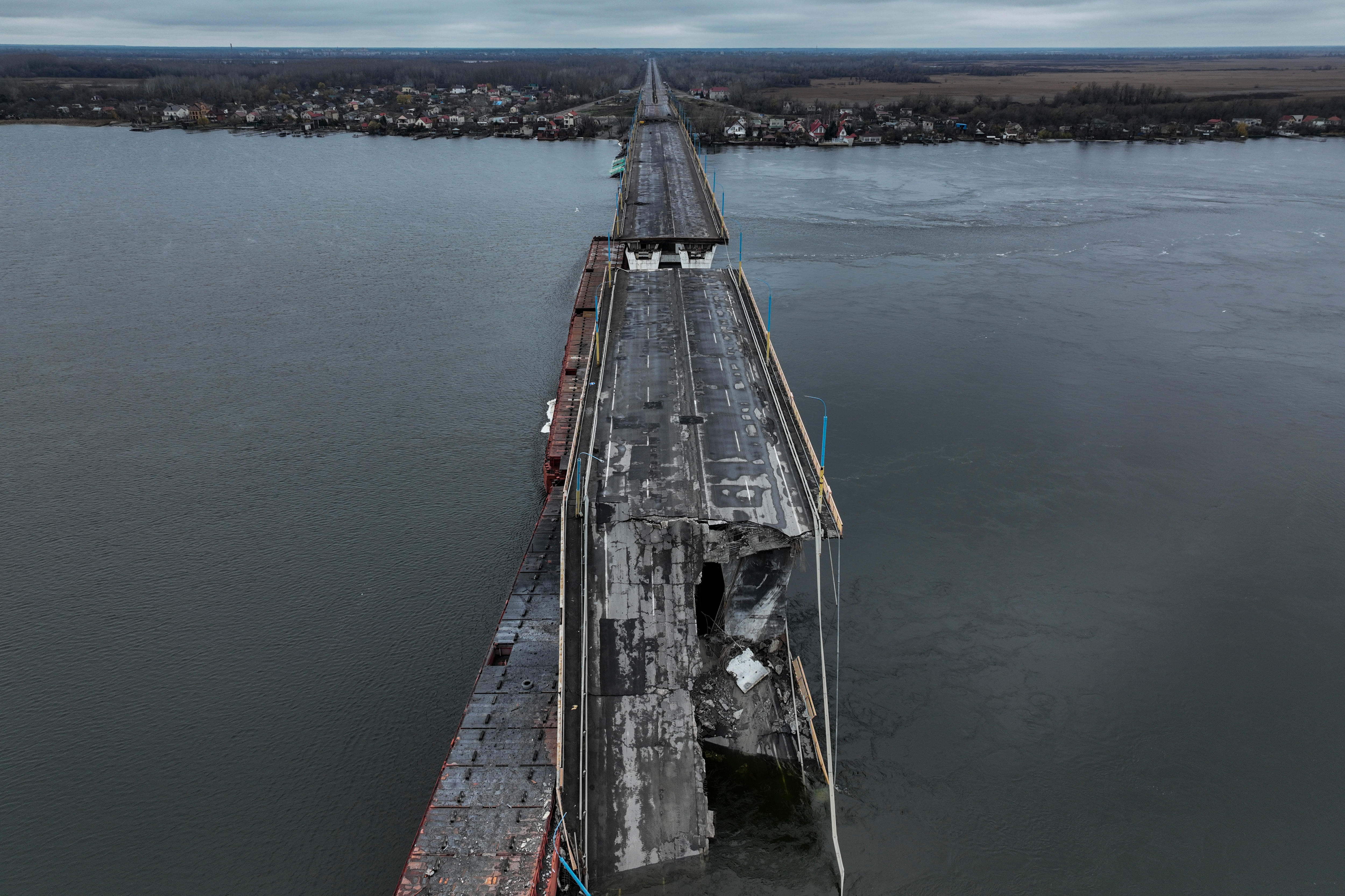 A view from over of the long bridge, with a section completely destroyed and falling into the water. 