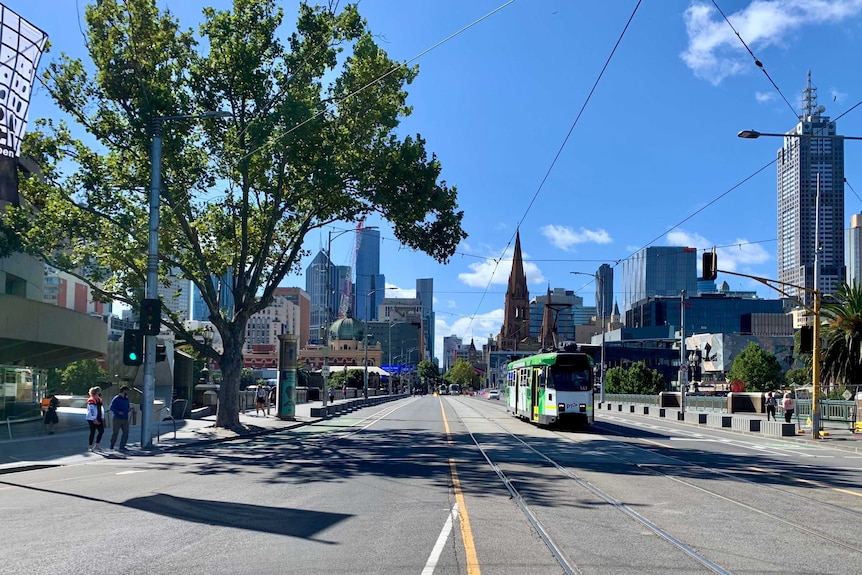 A wide shot of Melbourne with a tram and only several people.