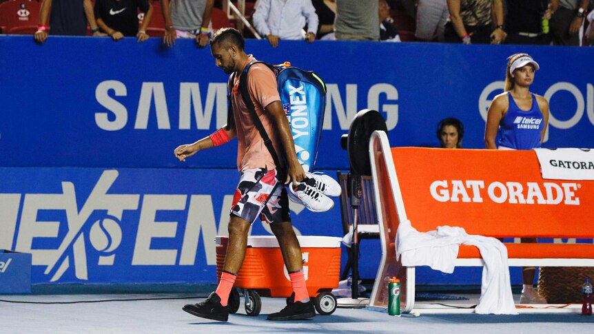 A male tennis player walks off the court with his bag on his back and his head down in Acapulco.