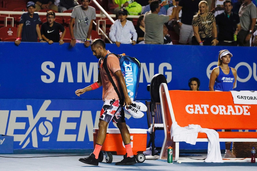 A male tennis player walks off the court with his bag on his back and his head down in Acapulco.