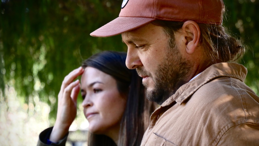A couple standing together. Man in red cap and woman with dark brown hair