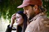 A couple standing together. Man in red cap and woman with dark brown hair