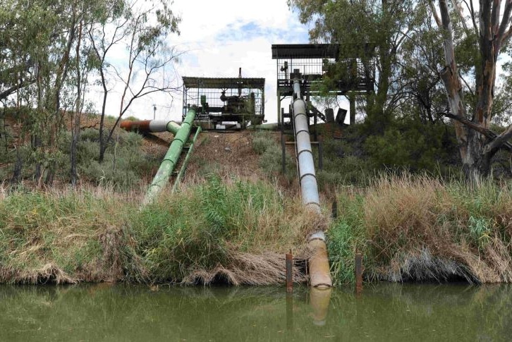 Large pumps running from the top of a river bank down into the river.