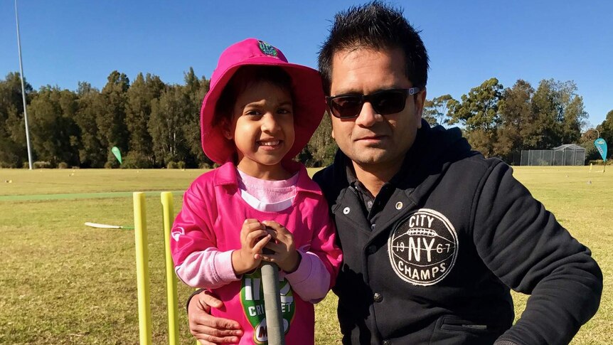 Five-year-old Sabine Bansal and father Sunny kneel with a cricket bat.