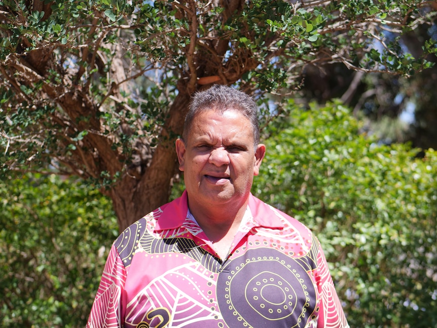 Portrait of an Indigenous man wearing a colourful shirt looking directly into the camera