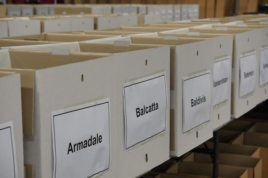 A row of boxes with the names of WA electorates printed on paper taped to the front.