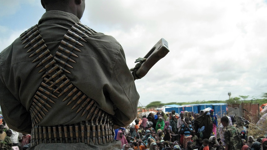 A member of the Islamist Al Shabaab militant group stands watch over Somalis at an aid-distribution camp in southern Mogadishu.