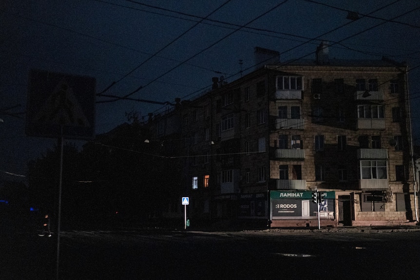 A man crosses a pitch-black street in Kharkiv as the city are in blackout. 