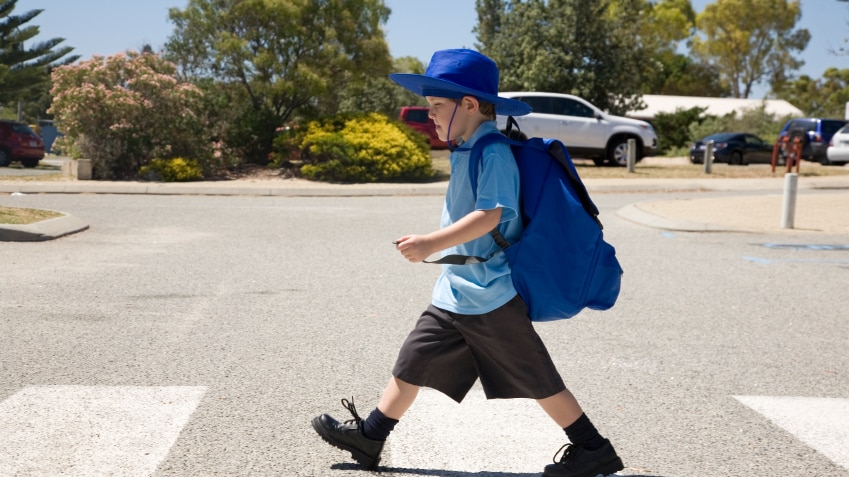 A small boy walking across a pedestrian crossing