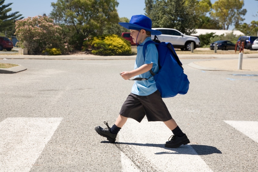 A small boy walking across a pedestrian crossing