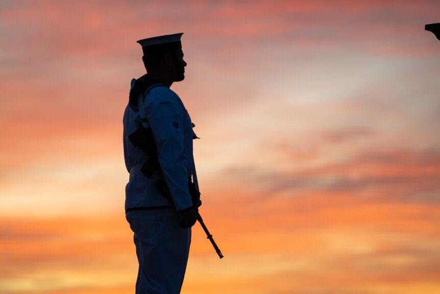 A man in uniform in silhouette at sunrise