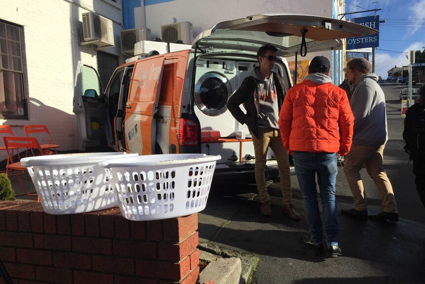 Three men behind the homeless laundry van.