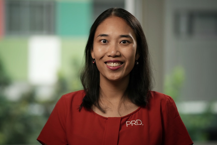 Diaswati Mardiasmo smiles at the camera, wearing a red shirt.