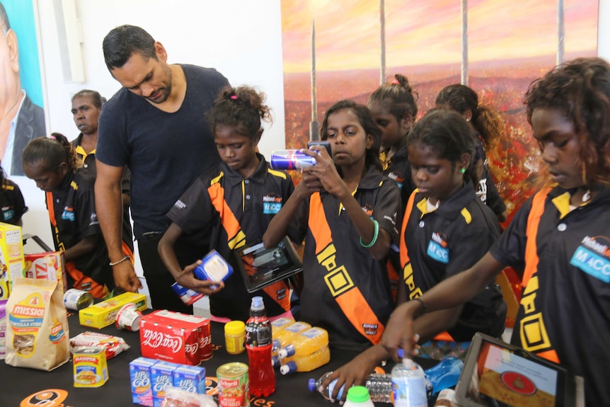 Rob Collins with several children using an app to scan barcodes on various food products.