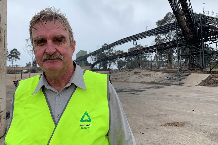 a picture of Kel Henry in high vis with a burnt out crane in the background