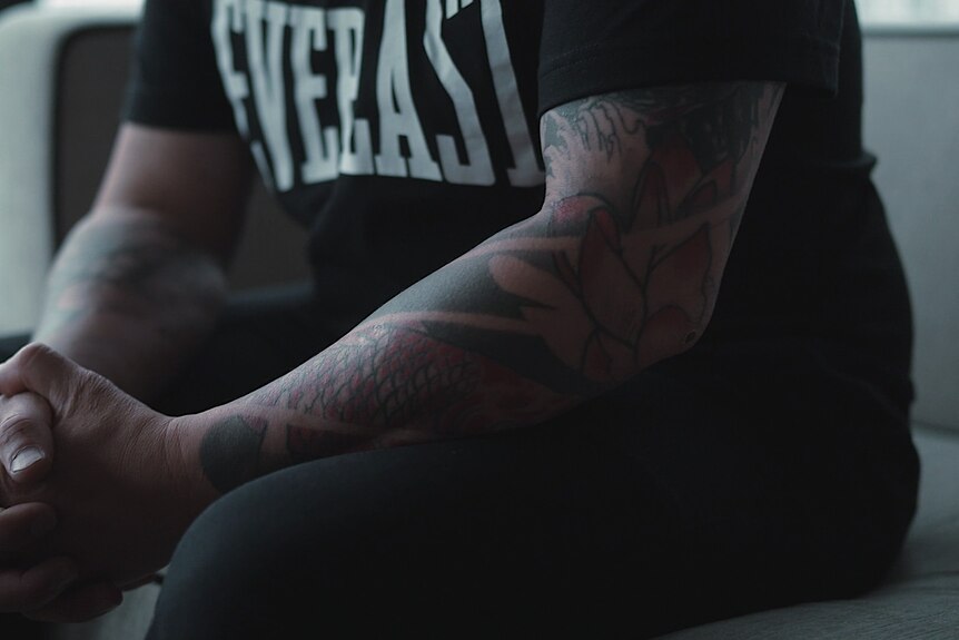 A man's arm with colourful sleeve tattoos.