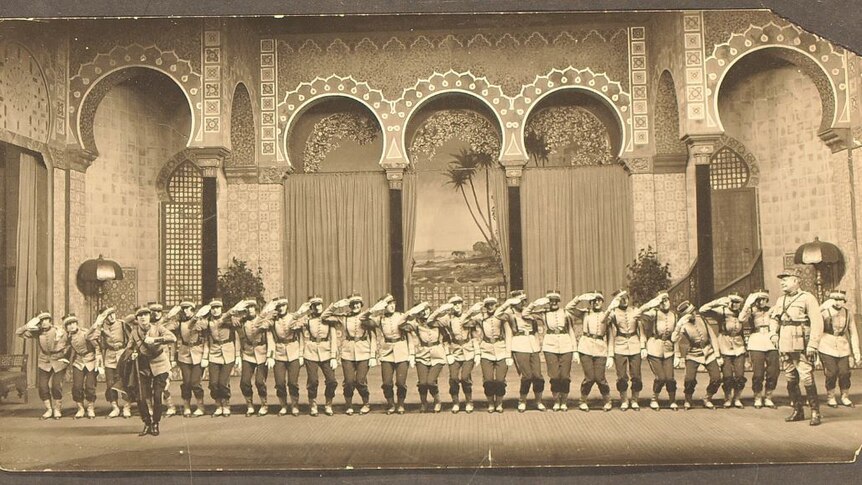 A black and white photo of an old theatre production, a long line of soldiers at attention