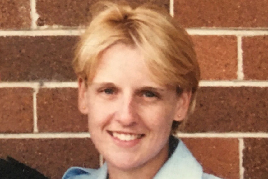 An old photo of a young woman in a blue uniform shirt.