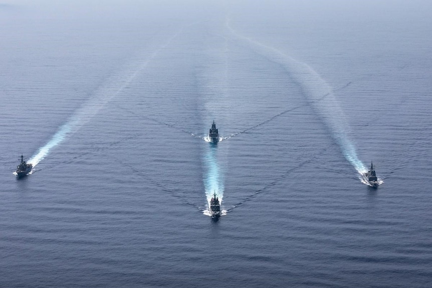 Four navy ships sailing in formation