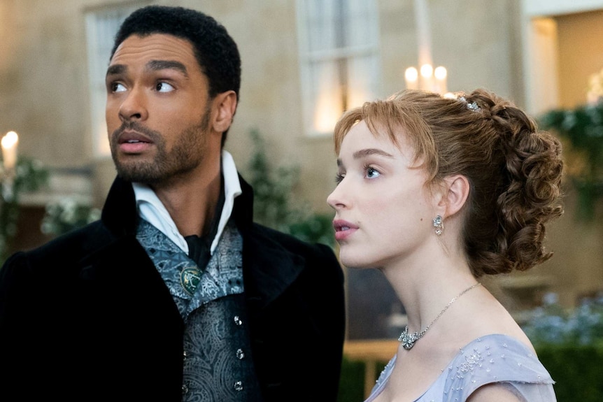Still from the Netflix regency romance series Bridgerton with Rege-Jean Page and Phoebe Dynevor at a fancy event