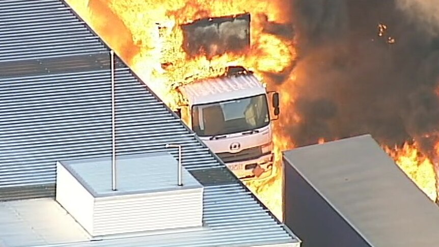 Orange flames engulf a truck as the factory fire rages.
