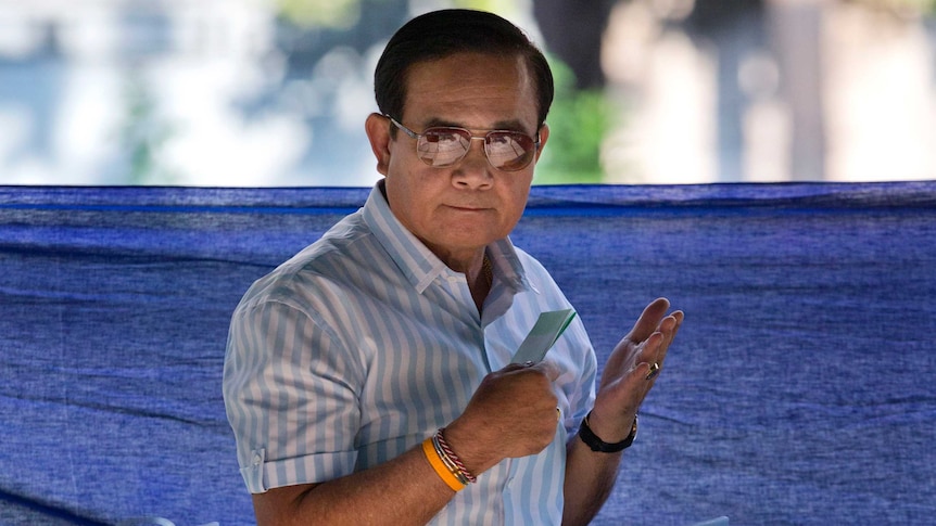 Thailand's Prime Minister Prayuth Chan-ocha wears aviators and holds his ballot in his hand at a polling station.