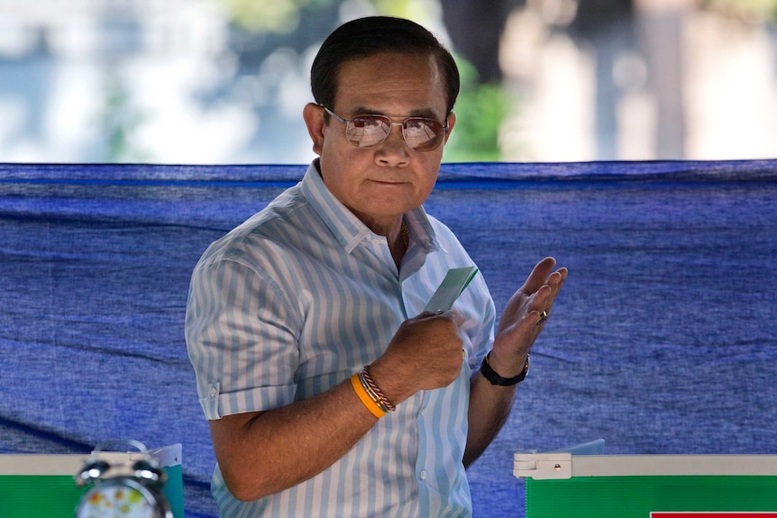 Thailand's Prime Minister Prayuth Chan-ocha wears aviators and holds his ballot in his hand at a polling station.