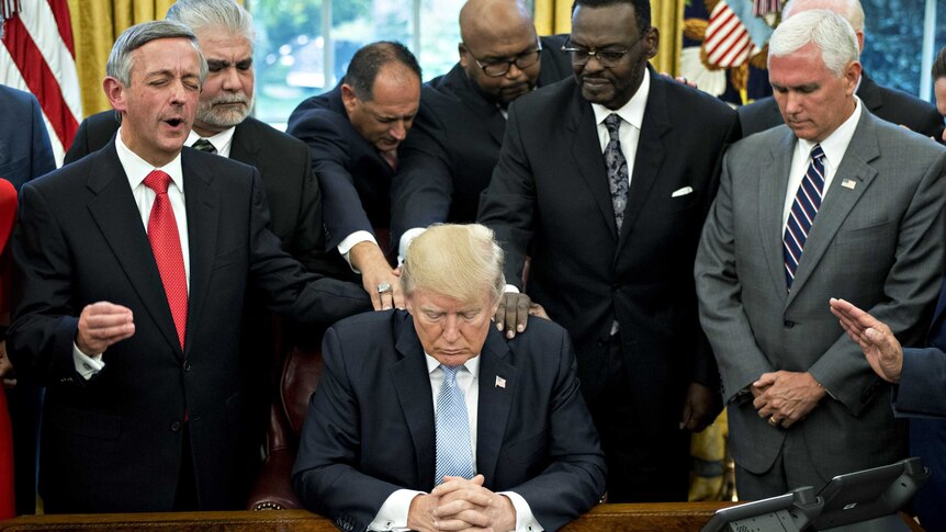U.S. President Donald Trump prays with faith leaders and evangelical ministers.