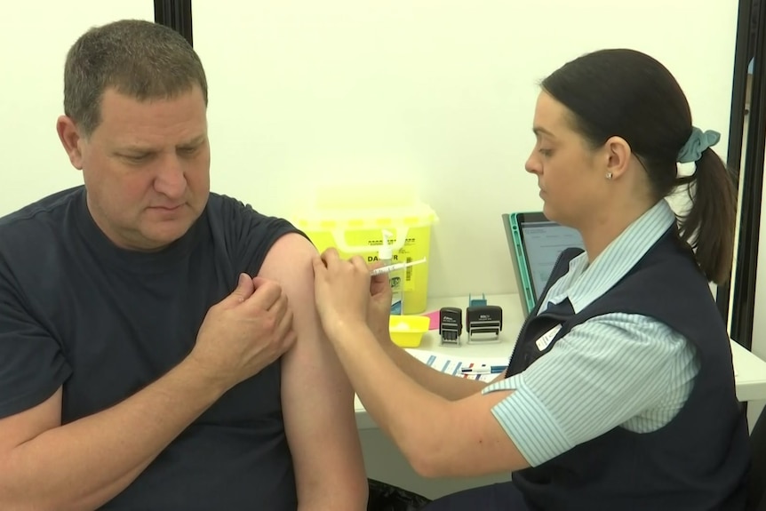 A woman injects a man both sitting down