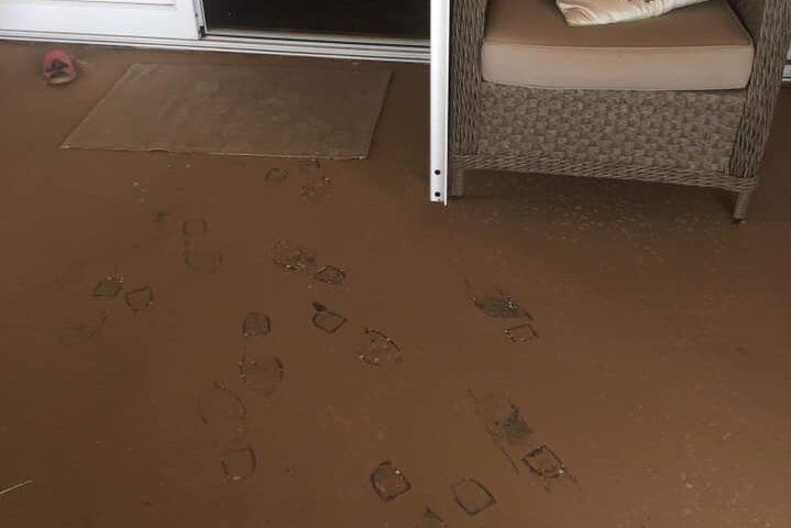 footprints in brown dust on the verandah of a house