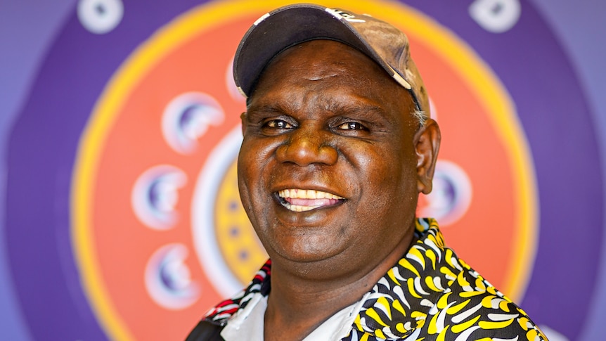 An Aboriginal man with a cap on smiling 