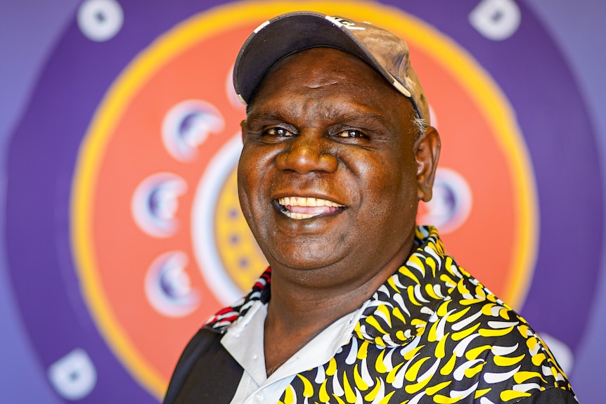 An Aboriginal man with a cap on smiling 