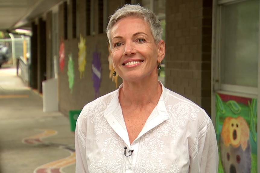 Kim Witt standing in front of a school building smiling 