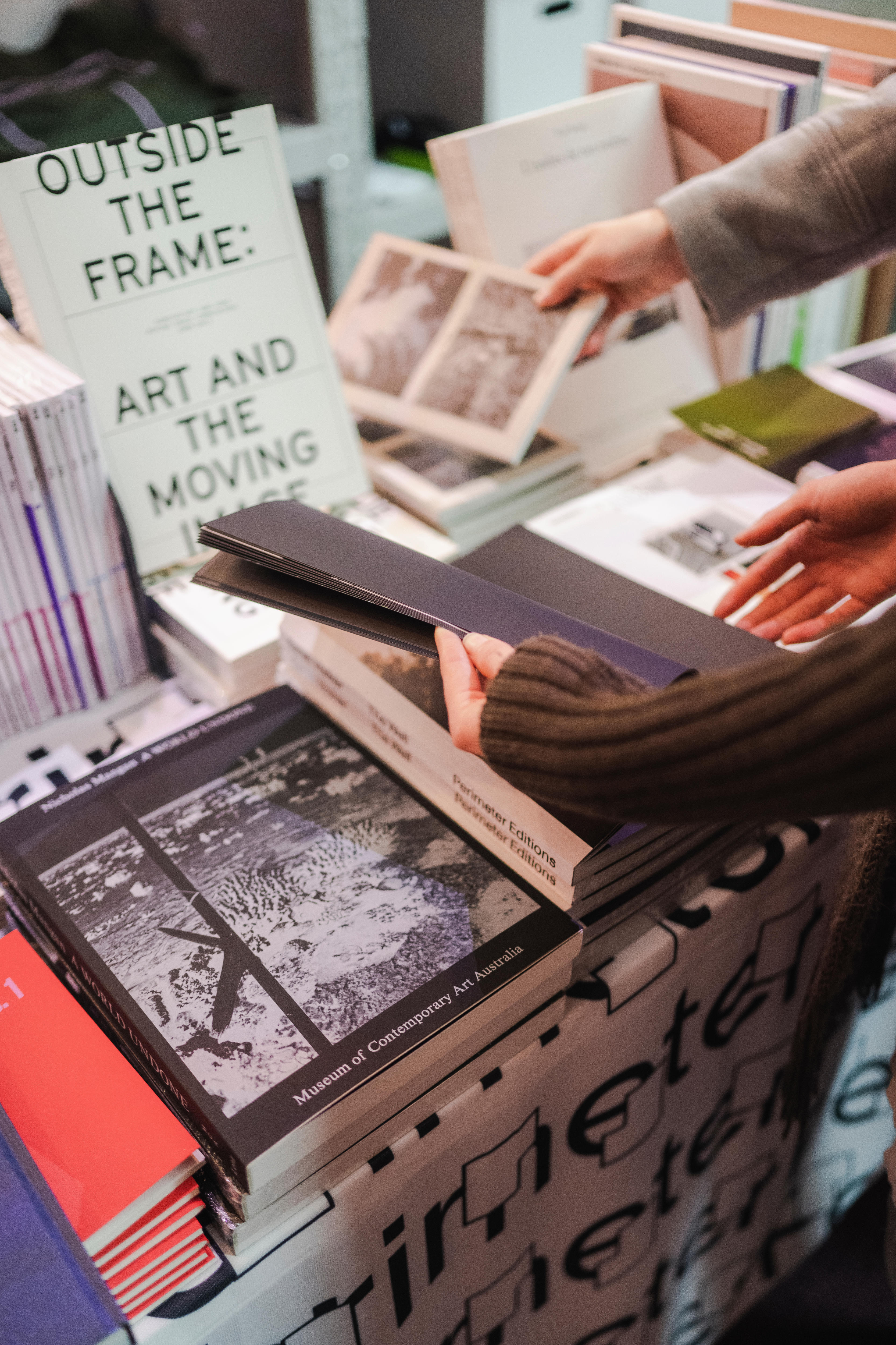 Close up image of various book covers stacked neatly next to each other, one with title, 'Outside the frame'.
