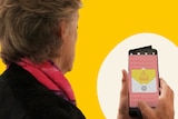 A woman facing away from the camera looks at a phone, for a story about scams.