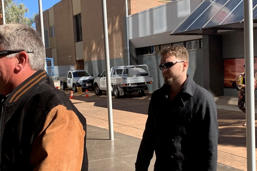 Oliver Deighton arriving in court, wearing a black jacket and sunglasses.