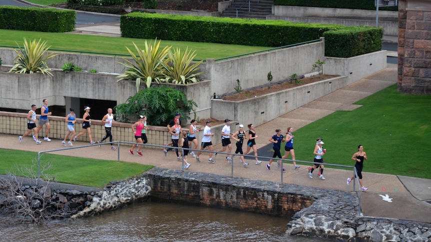 People jog along the walkway beside the Brisbane River.