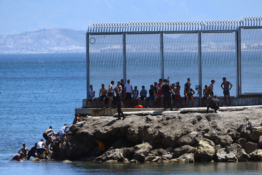 Gli ufficiali della Guardia civile spagnola stanno cercando di impedire ai marocchini di entrare nel territorio spagnolo.