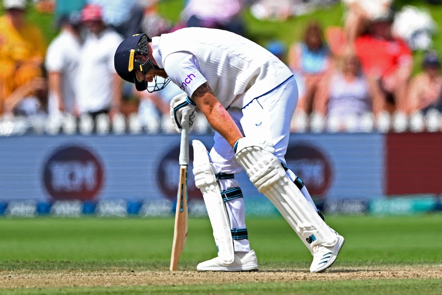 England cricket captain Ben Stokes bends over the crease in discomfort as he holds his left knee.