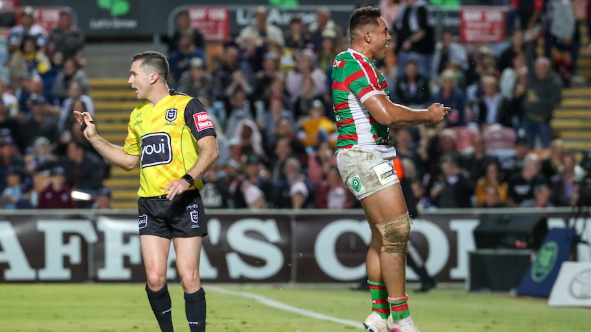 An NRL player leaps in triumph in the in-goal after scoring a try.