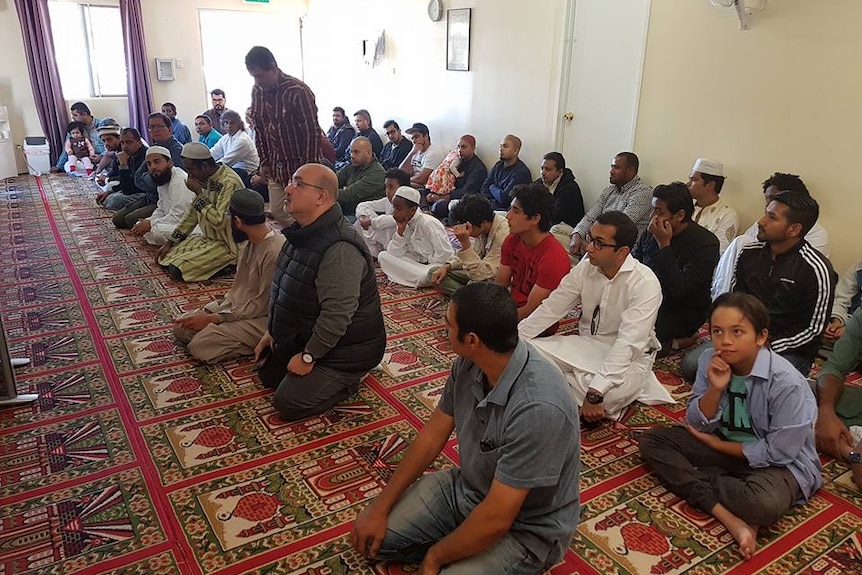 A group of men kneel on the floor as they pray.